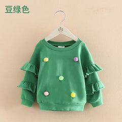 Girls green pom pom jumper with ruffle sleeves for ages 2-10 displayed on a hanger